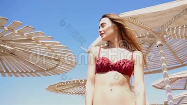 穿着泳衣的漂亮女孩站在沙滩伞上，向远处望去